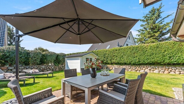 Une terrasse extérieure avec une table, des chaises et un grand parasol.