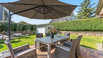 An outdoor patio with a table, chairs, and a large umbrella.