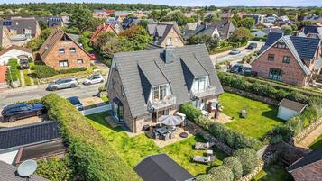En boligejendom med et stort hus, skråt tag, velplejet græsplæne og en parabolantenne.