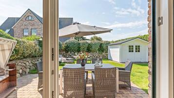 An outdoor patio with a table and chairs, a covered umbrella, and a stone wall.