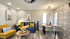 A modern living room with a sofa, coffee table, and a dining area with a table and chairs.