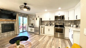 A modern kitchen with white cabinets, stainless steel appliances, and a black and white patterned backsplash.