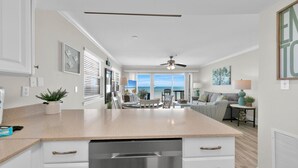 A kitchen with a large island, white cabinetry, and a view to the outside. - Third Floor End Unit,  Beach service included, 2 chairs & 1 umbrella, Mar-Oct (Santa Rosa Beach)