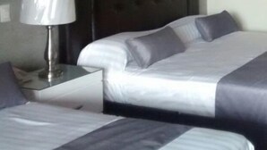 Habitació d'hotel amb dos llits, una taula de nit i una làmpada.