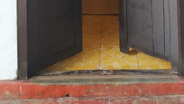 Una porta amb dues portes tancades, un lluminari a la part superior i un tamboret petit al fons.