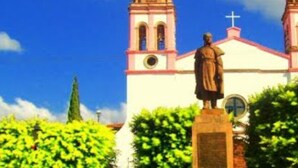 Una església amb una torre campanar i una estàtua al davant.