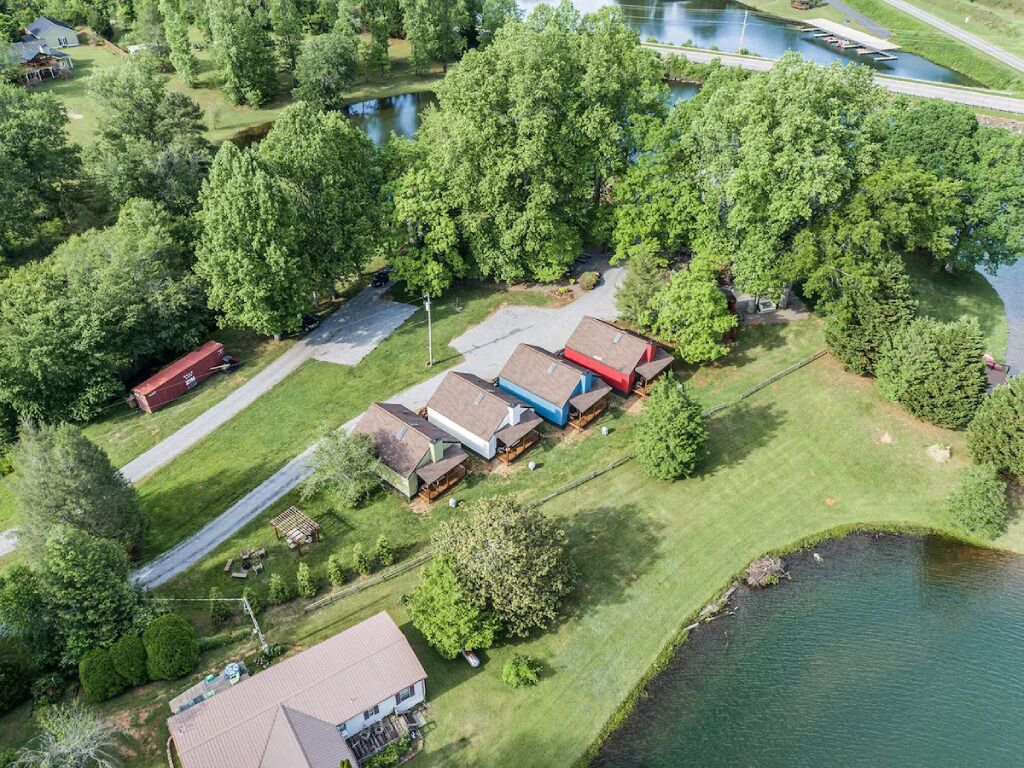 Vue aérienne d’une propriété au bord du lac, comprenant plusieurs bâtiments, un quai et une route.