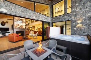 A modern outdoor living area with a stone wall, a hot tub, and a fire feature.
