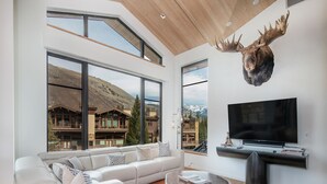 A modern living room with a large sofa, a round coffee table, and a mounted television.