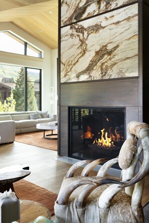 A modern living room with a fireplace, a sofa, and a decorative chair with antlers.
