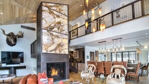 A spacious living area with a fireplace, leather sofa, and dining area with unique chairs.