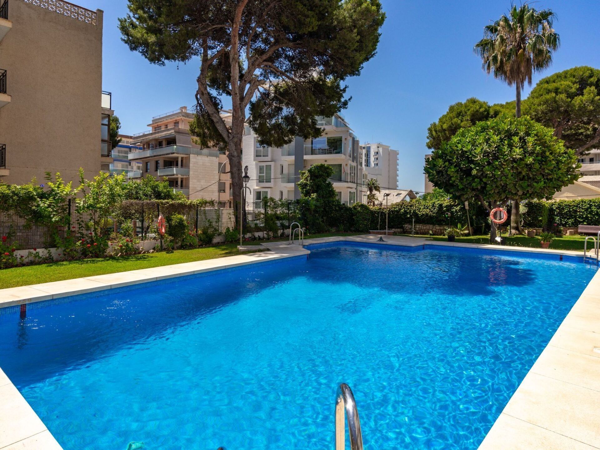 Une piscine entourée de verdure et de bâtiments modernes.