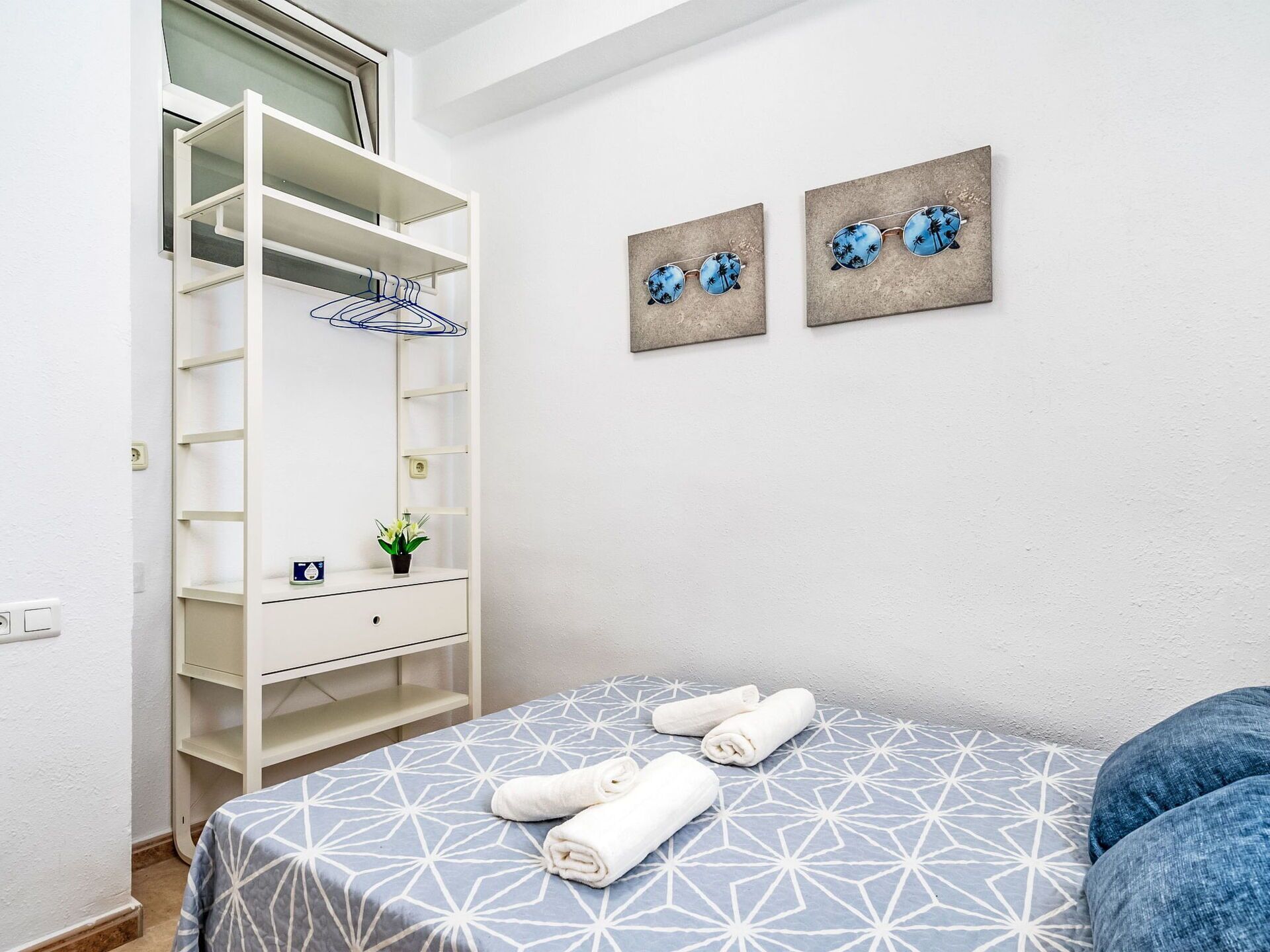 Een slaapkamer met een bed, een witte kledingkast en twee decoratieve wandpanelen.
