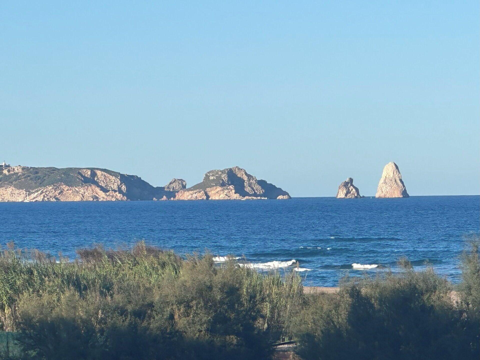 A coastal landscape with rocky outcrops and a lighthouse in the distance.