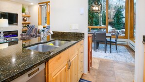 A modern kitchen with granite countertops, wooden cabinets, and a Bosch dishwasher. - Millrace 6-A | Cozy 2BR Condo, Creek Views, Vail Cascade (Vail)