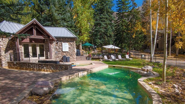 A stone building with a pool, surrounded by trees and a clear sky. - Millrace 6-A | Cozy 2BR Condo, Creek Views, Vail Cascade (Vail)