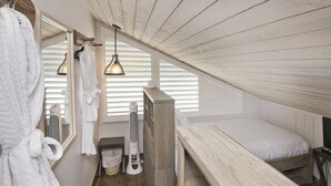 Une chambre avec un lit superposé en bois, une table de chevet, un miroir et un luminaire suspendu.