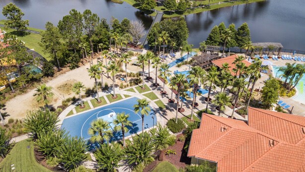 An aerial view of a resort with a swimming pool, palm trees, and a tennis court. - 3BR Townhome Near Disney I Resort Pool, Hot Tub & Disney-Themed Room (Kissimmee)
