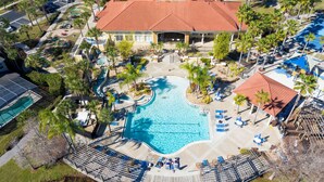 An aerial view of a resort with a central swimming pool, palm trees, and a red-roofed building. - 3BR Townhome Near Disney I Resort Pool, Hot Tub & Disney-Themed Room (Kissimmee)