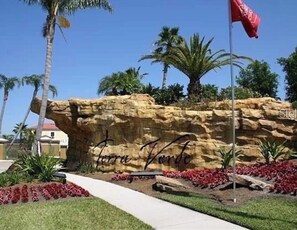 Stroll through the beautifully landscaped grounds featuring a striking rock formation and vibrant red flowering plants.