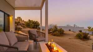 An outdoor seating area with a fire feature, overlooking a desert landscape.