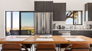 A modern kitchen with a large island, stainless steel appliances, and a view of the desert landscape.