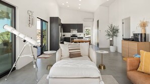 A modern living room with a telescope, a sofa, a coffee table, and a dining area in the background.