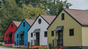 A row of colorful, single-story buildings with a uniform architectural style, each featuring a front entrance and a small porch area.