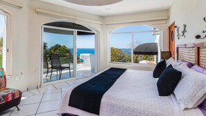 Un dormitorio con una cama grande, vista al mar y puerta corrediza que da a un balcón.