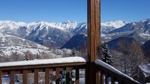 Un balcón de madera con vista a montañas nevadas.