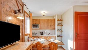 Una cocina con armarios de madera, microondas, cafetera y una mesa de comedor con sillas.