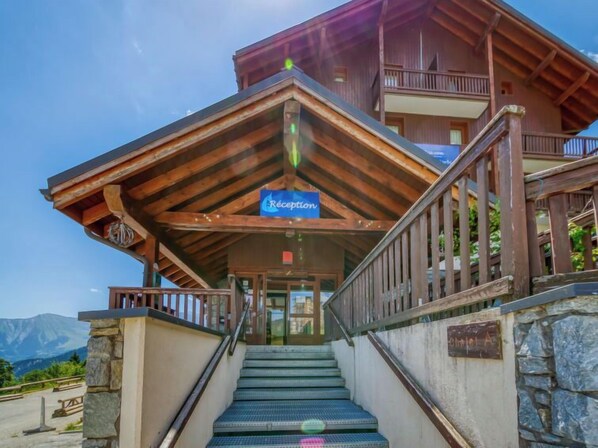 Un edificio de madera con área de recepción, escaleras y un muro de piedra.