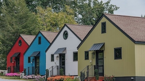 A row of colorful, single-story buildings with a uniform architectural style, each featuring a front entrance and a small porch area.