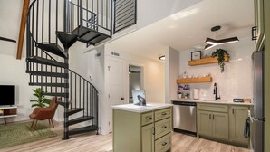 A modern kitchen with a built-in dishwasher, a wooden countertop, and a hanging plant.