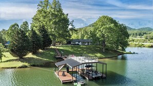 Une propriété au bord du lac, dotée d’un quai, d’un espace de repos couvert et d’une maison en arrière-plan.