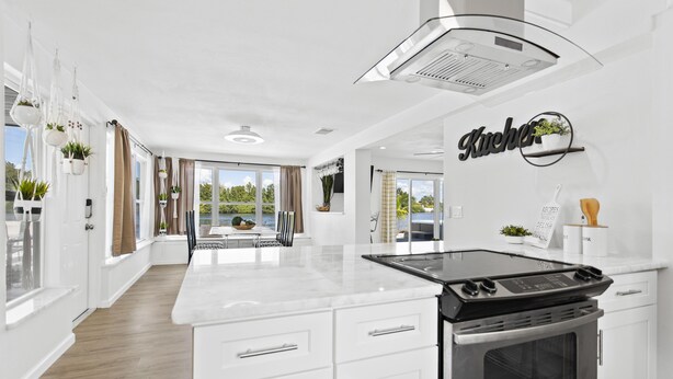 Una cocina moderna con armarios blancos, estufa integrada y una isla grande.