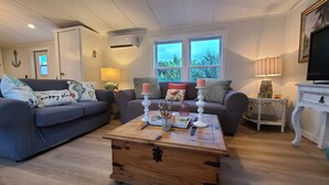 A cozy living room with two sofas, a wooden coffee table, and a TV. - 200ft of Waterfront with Tiki & Heated Pool - Boaters Paradise  (Key Largo)