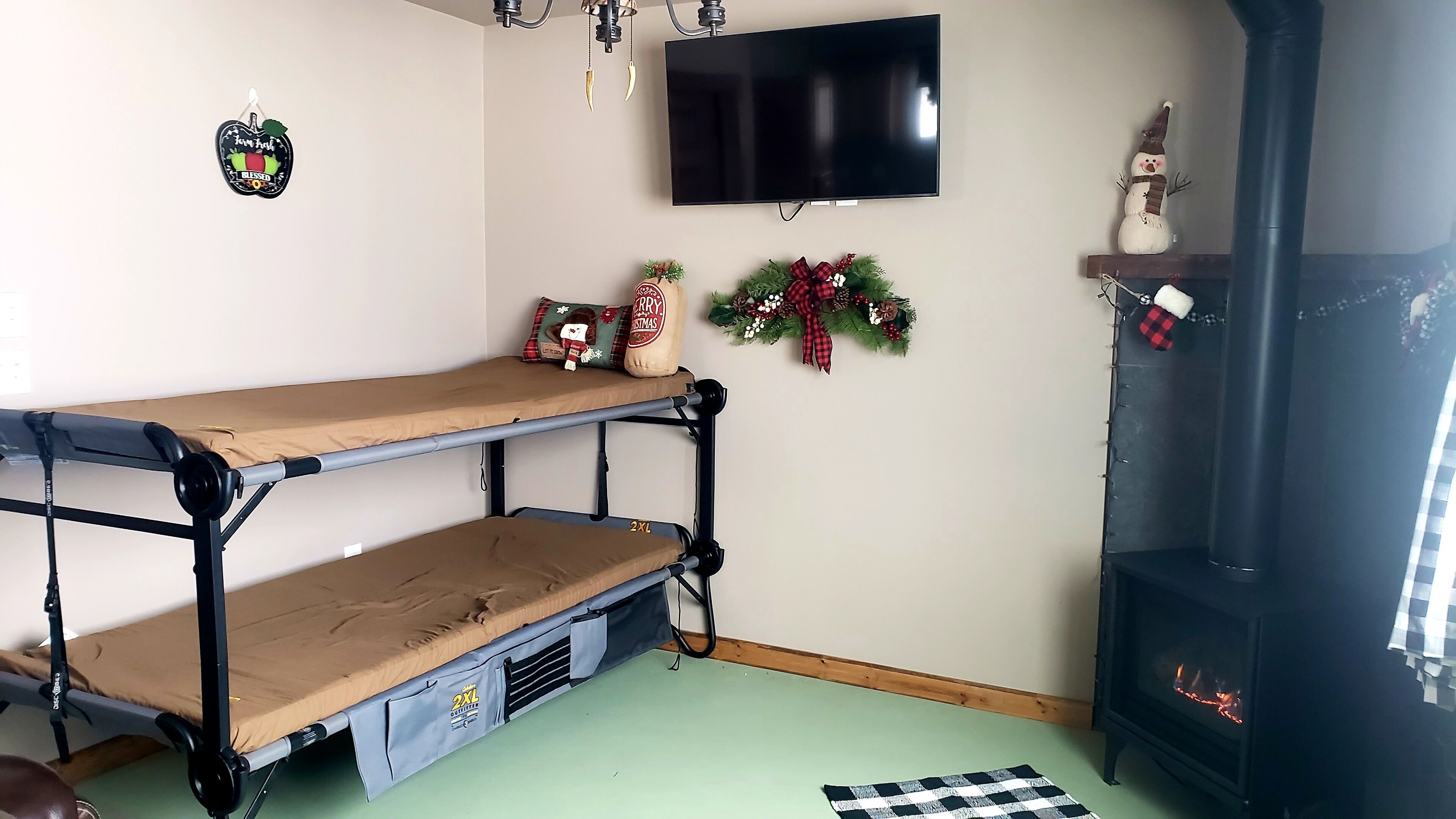 Una cama individual con una televisión encima, una chimenea y decoración navideña.