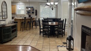 Un vaste salon doté d’un parquet, un coin repas agrémenté d’un lustre, et un téléviseur fixé au mur.