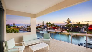 A balcony with a view of a marina and buildings, furnished with white chairs and a table. - Stunning Waterfront home on the Gold Coast*Heated Pool* 
Pet Friendly. (Surfers Paradise)