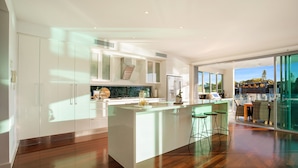 A modern kitchen with a central island, bar stools, and a view of the outdoors. - Stunning Waterfront home on the Gold Coast*Heated Pool* 
Pet Friendly. (Surfers Paradise)