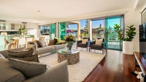 A modern living room with a sofa, armchairs, a coffee table, and a television. - Stunning Waterfront home on the Gold Coast*Heated Pool* 
Pet Friendly. (Surfers Paradise)