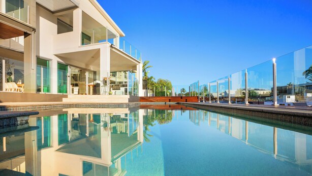 A modern hotel with a clear pool reflecting the building and palm trees. - Stunning Waterfront home on the Gold Coast*Heated Pool* 
Pet Friendly. (Surfers Paradise)