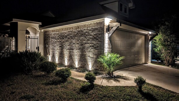 A residential building with a brick facade, a garage, and a well-lit entrance.