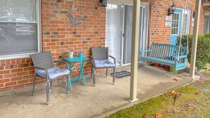 Eine überdachte Veranda mit zwei Korbstühlen, einem kleinen Tisch und einer blauen Bank.