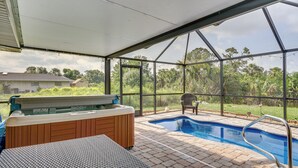 Piscina esterna coperta con idromassaggio e area relax, circondata da una struttura in vetro con vista sul verde.