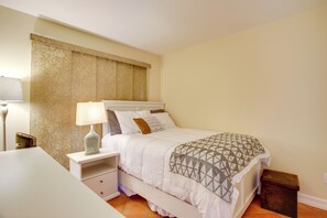 Une chambre à coucher avec un lit, une table de chevet, une lampe et une petite commode en bois.