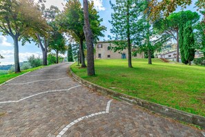 A paved pathway leading to a stone building with a blue door, surrounded by trees and grass. - Villa in Pesaro with 4 bedrooms sleeps 10 (Novilara)