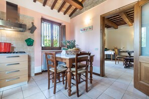 A kitchen with wooden cabinets, a stove, and a dining area with a table and chairs. - Villa in Pesaro with 4 bedrooms sleeps 10 (Novilara)