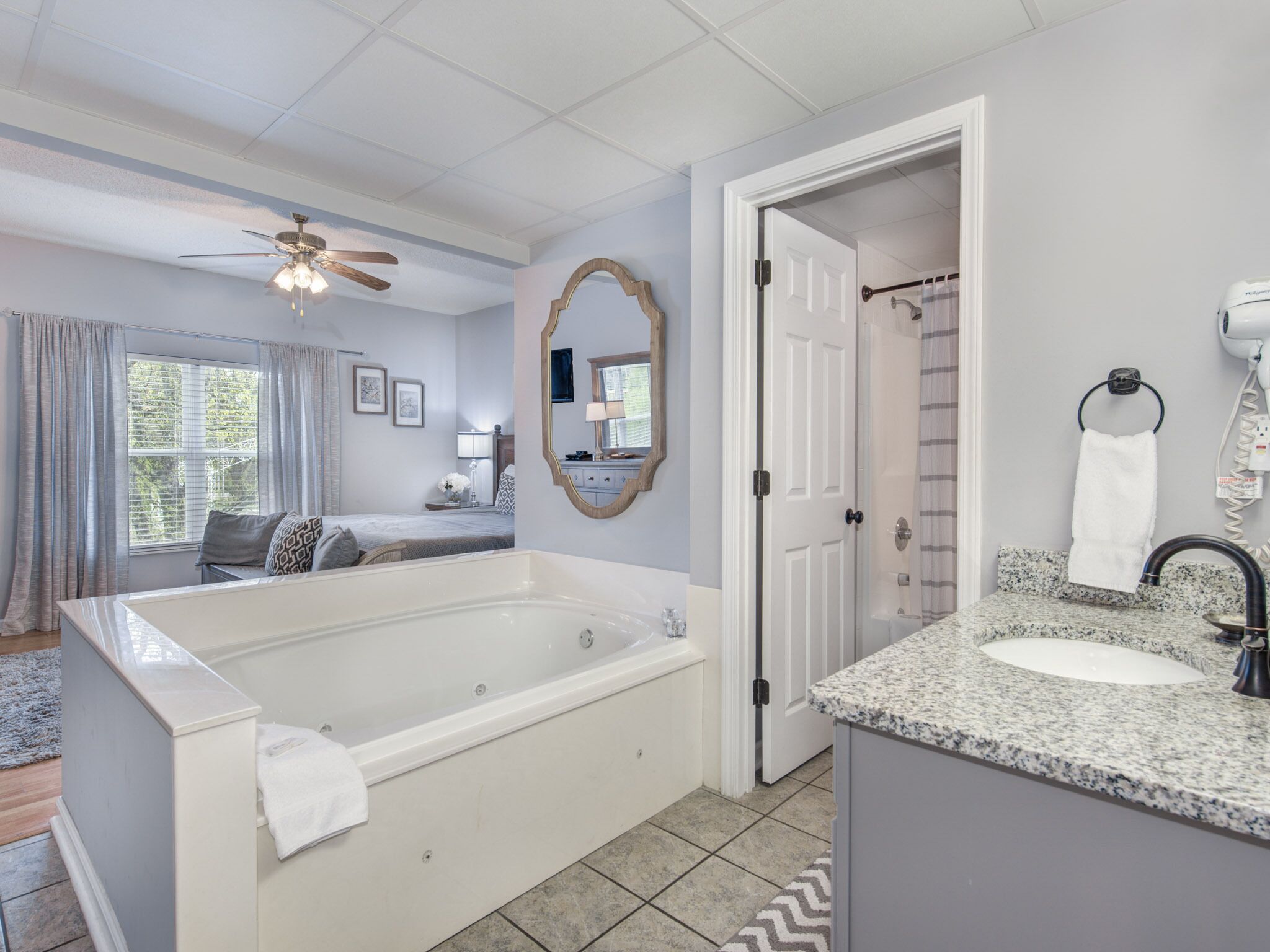 A modern bathroom with a large bathtub, a vanity with a sink, and a ceiling fan.